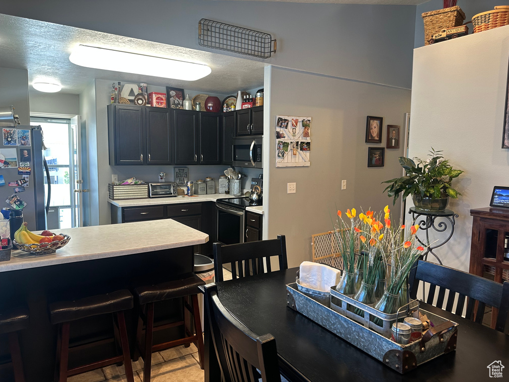 Kitchen featuring stainless steel appliances, light countertops, and a breakfast bar area