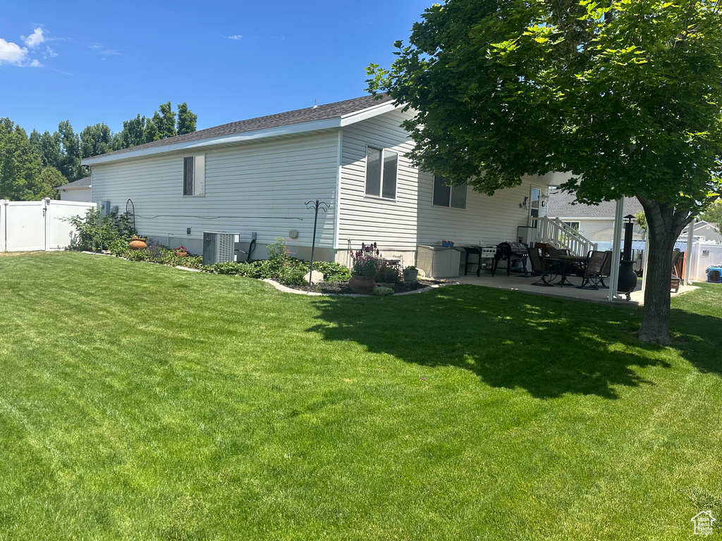 Back of property with a patio area, central AC unit, and roof with shingles
