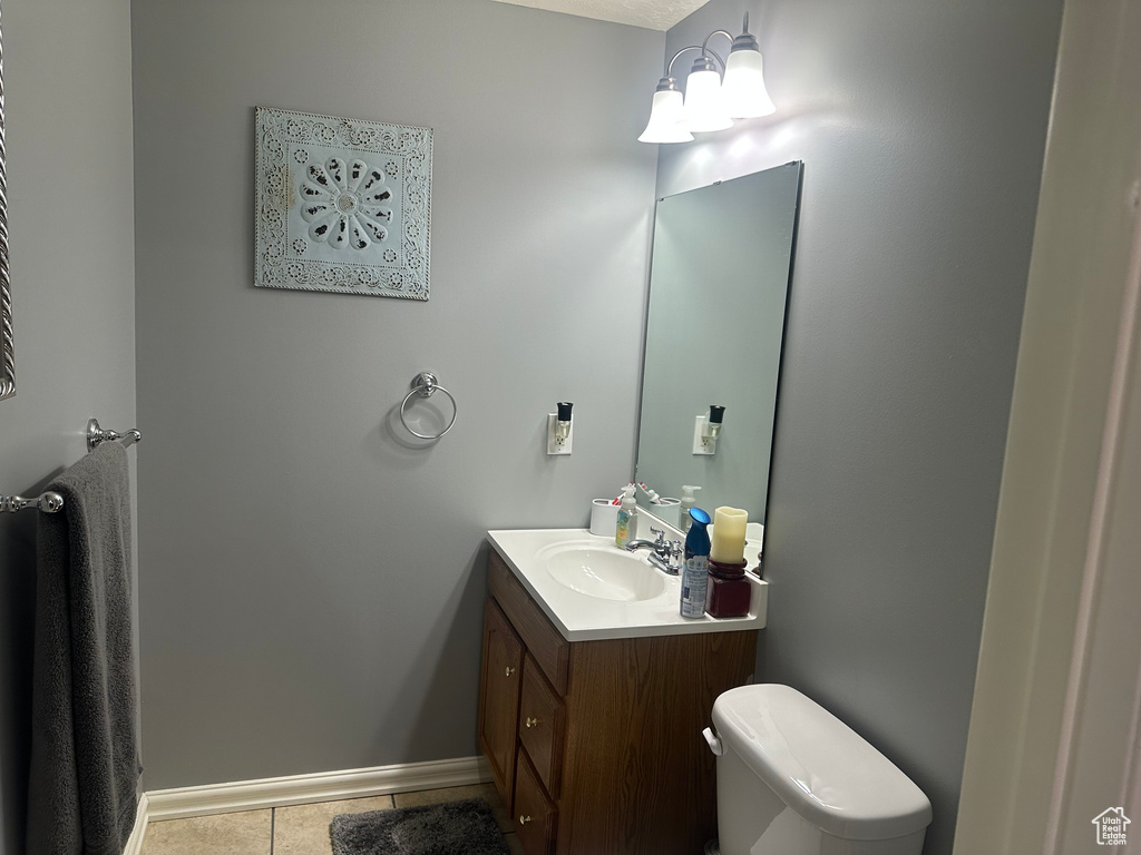 Half bathroom with vanity, tile patterned flooring, toilet, and baseboards