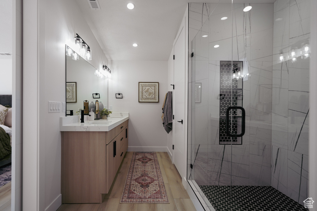 Ensuite bathroom featuring vanity, a stall shower, baseboards, wood finished floors, and recessed lighting