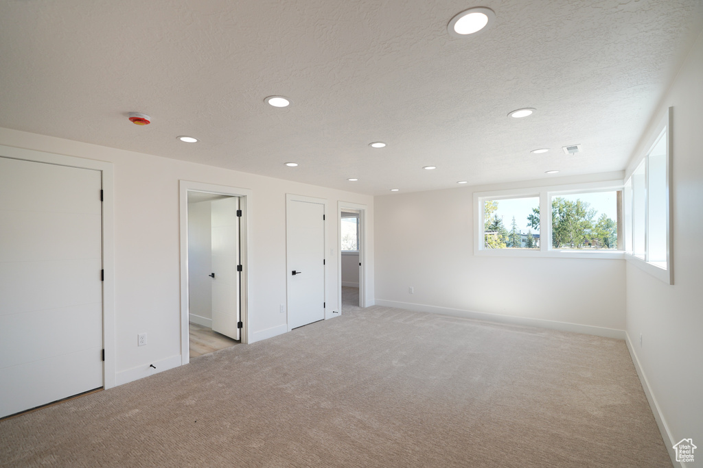 Unfurnished bedroom featuring light carpet, recessed lighting, baseboards, and a textured ceiling