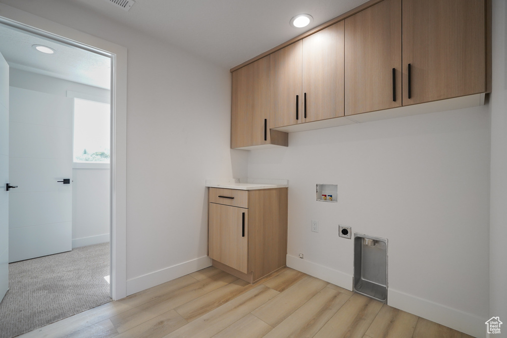 Washroom featuring electric dryer hookup, hookup for a washing machine, cabinet space, light wood-style flooring, and recessed lighting
