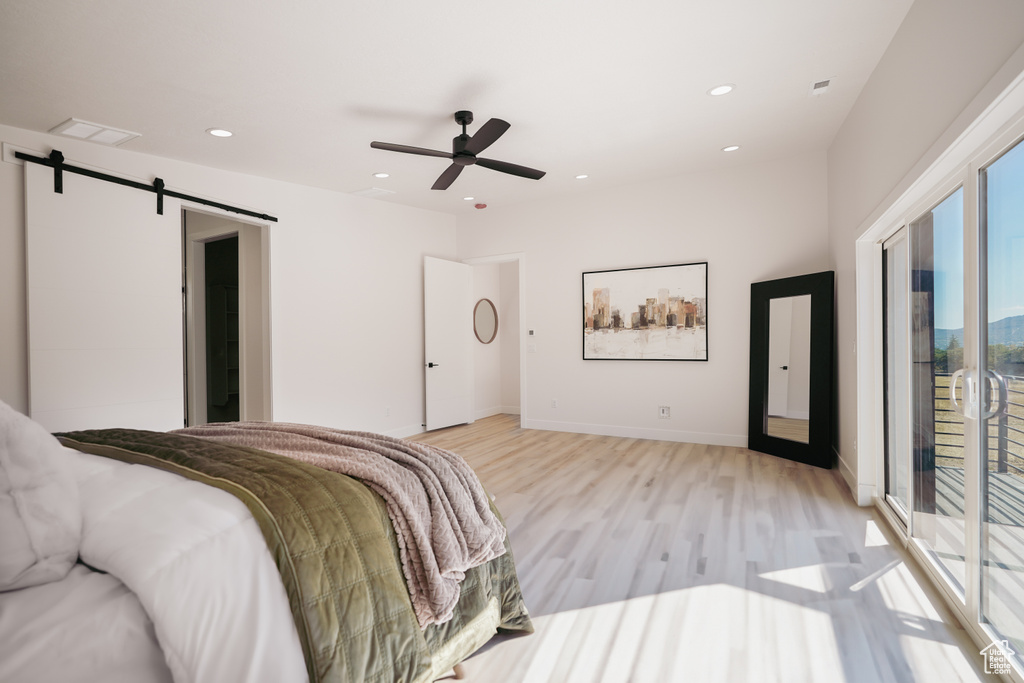 Bedroom featuring light wood-type flooring, access to exterior, a barn door, recessed lighting, and ceiling fan