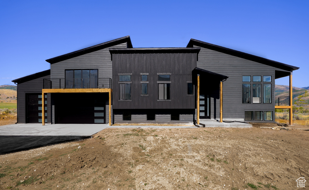 Contemporary house with a balcony, driveway, an attached garage, and a mountain view