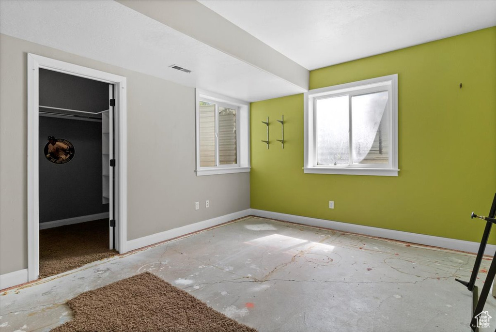 Unfurnished bedroom with multiple windows, a walk in closet, and baseboards