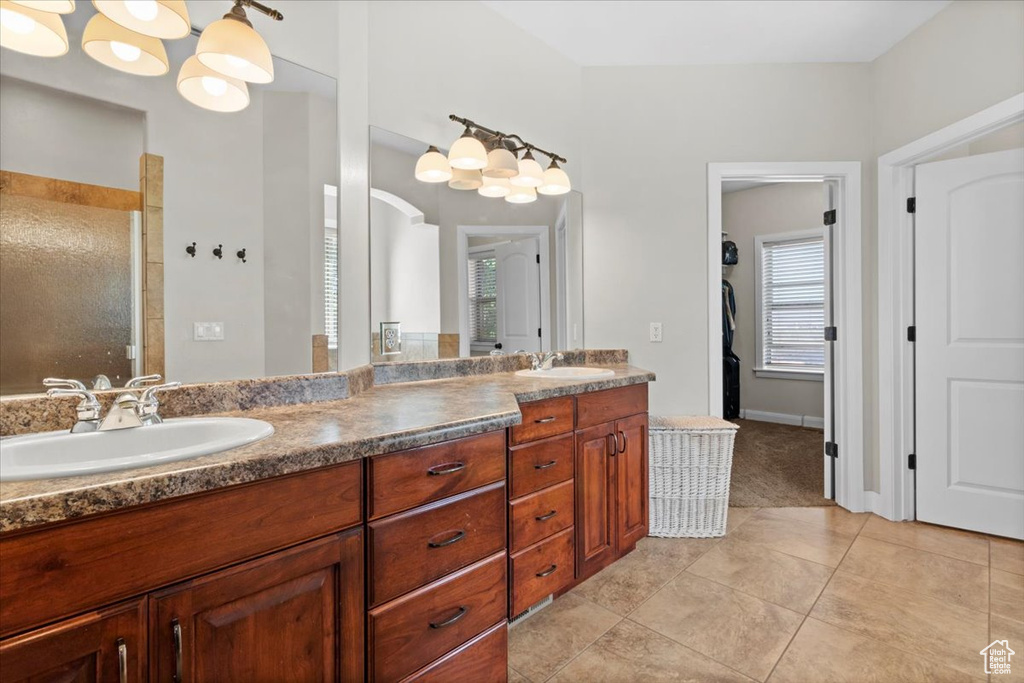 Full bathroom with double vanity, a tile shower, and tile patterned floors