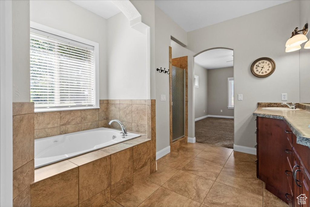 Bathroom featuring vanity, a bath, a stall shower, baseboards, and tile patterned flooring