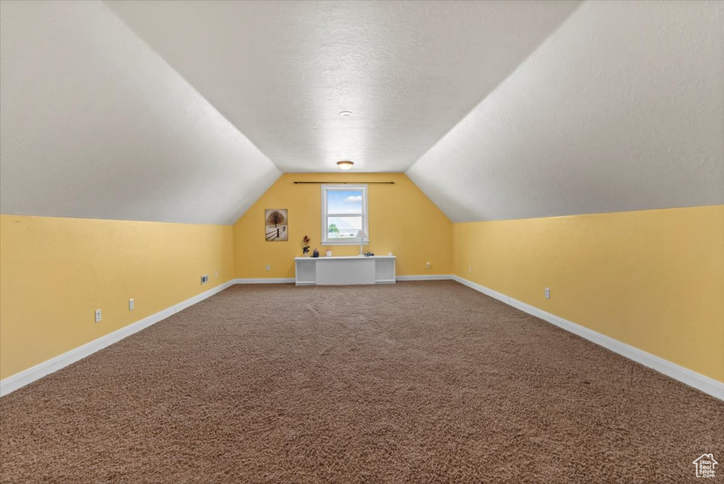 Additional living space with baseboards, lofted ceiling, carpet floors, and a textured ceiling