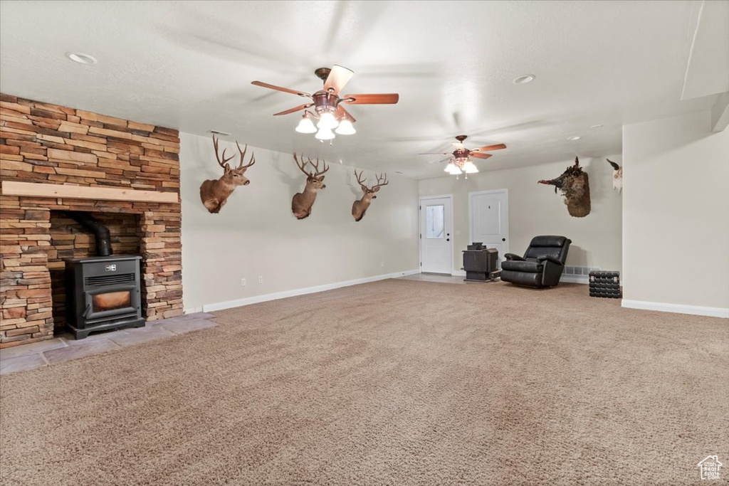 Unfurnished living room featuring a ceiling fan, a wood stove, carpet flooring, baseboards, and recessed lighting