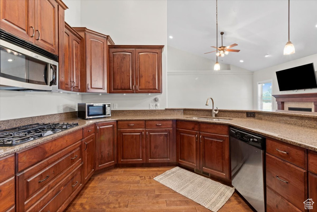 Kitchen with stainless steel appliances, a sink, a ceiling fan, lofted ceiling, and dark wood finished floors
