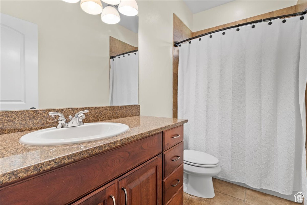 Bathroom with vanity, toilet, tile patterned flooring, and curtained shower