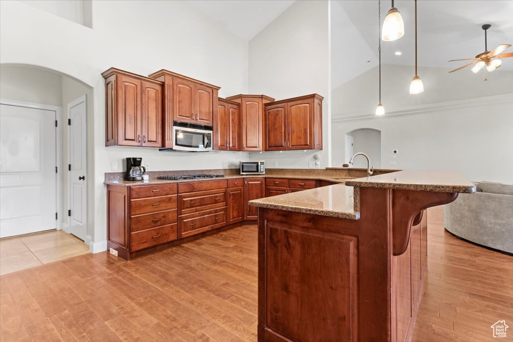 Kitchen with stainless steel appliances, high vaulted ceiling, open floor plan, a breakfast bar area, and a ceiling fan