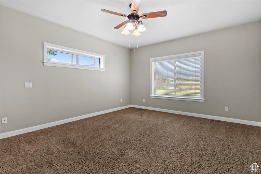 Unfurnished room with plenty of natural light, a ceiling fan, baseboards, and carpet flooring