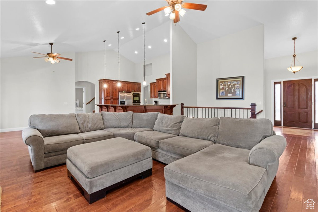 Living area featuring ceiling fan, arched walkways, high vaulted ceiling, recessed lighting, and wood finished floors
