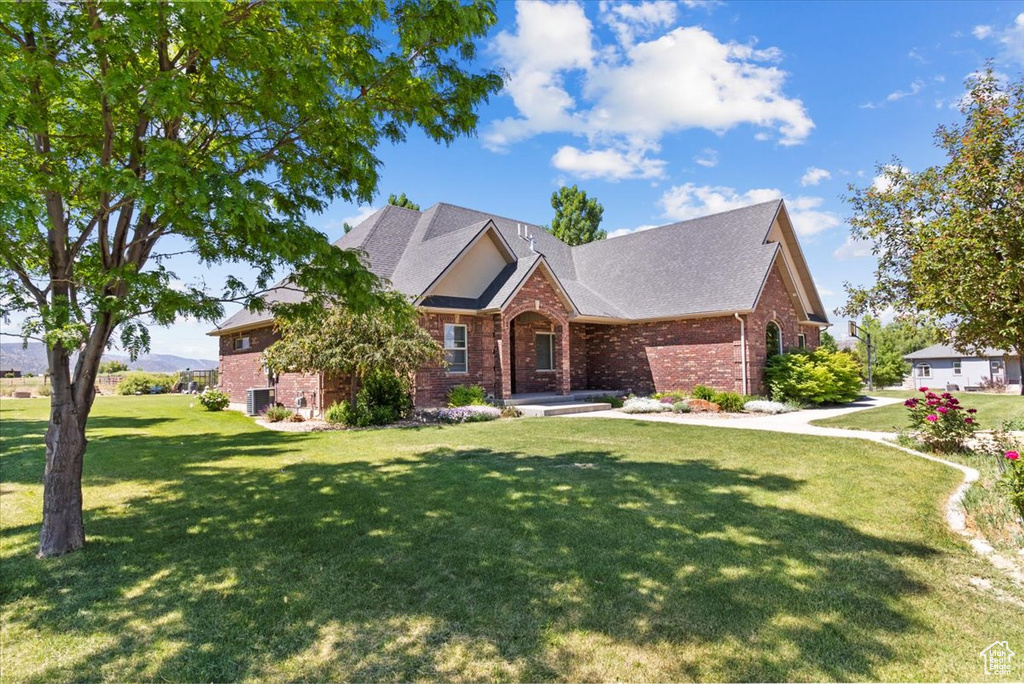 Traditional-style house featuring brick siding, a front lawn, and roof with shingles