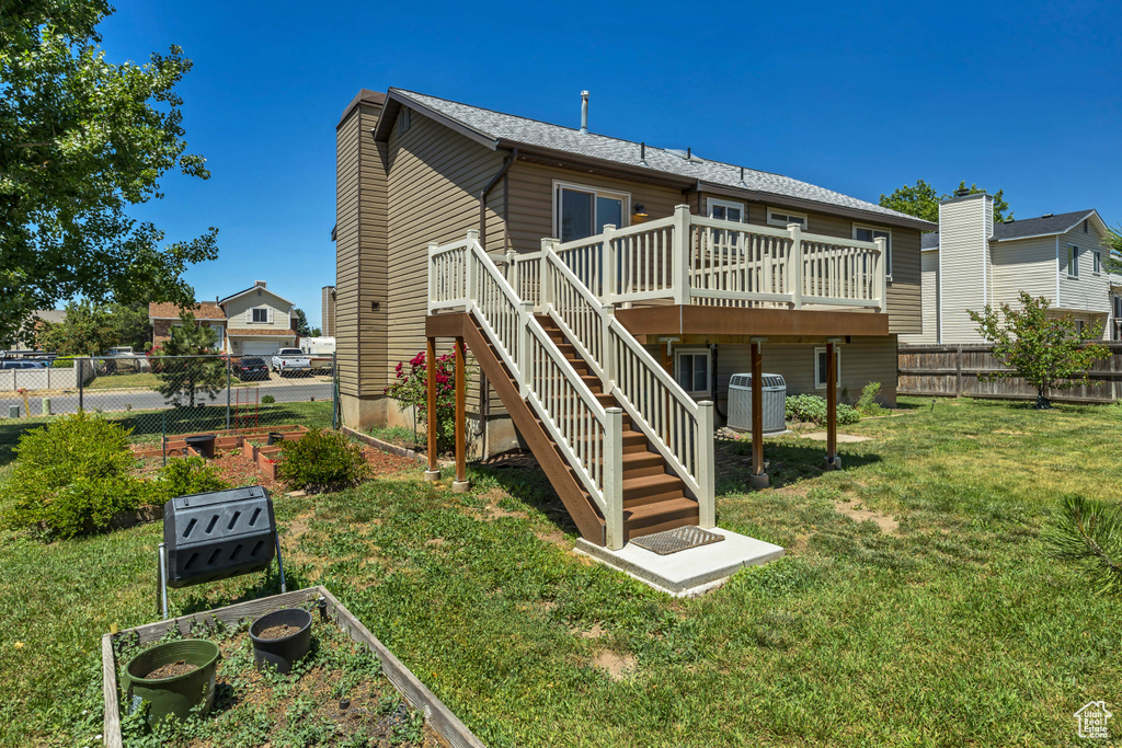 Back of house with a deck, a vegetable garden, stairway, and cooling unit
