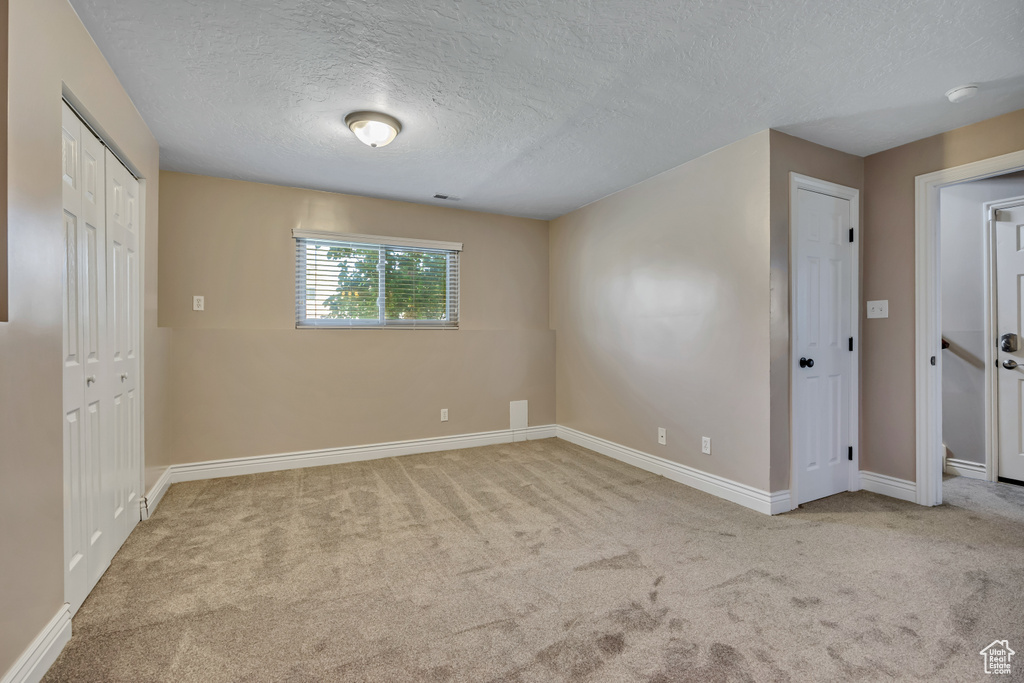 Unfurnished bedroom featuring carpet floors, a textured ceiling, and baseboards