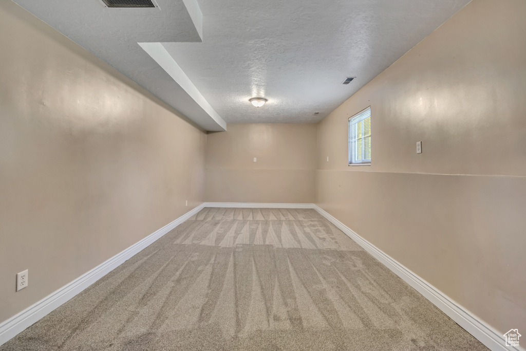 Basement with a textured ceiling, carpet floors, and baseboards