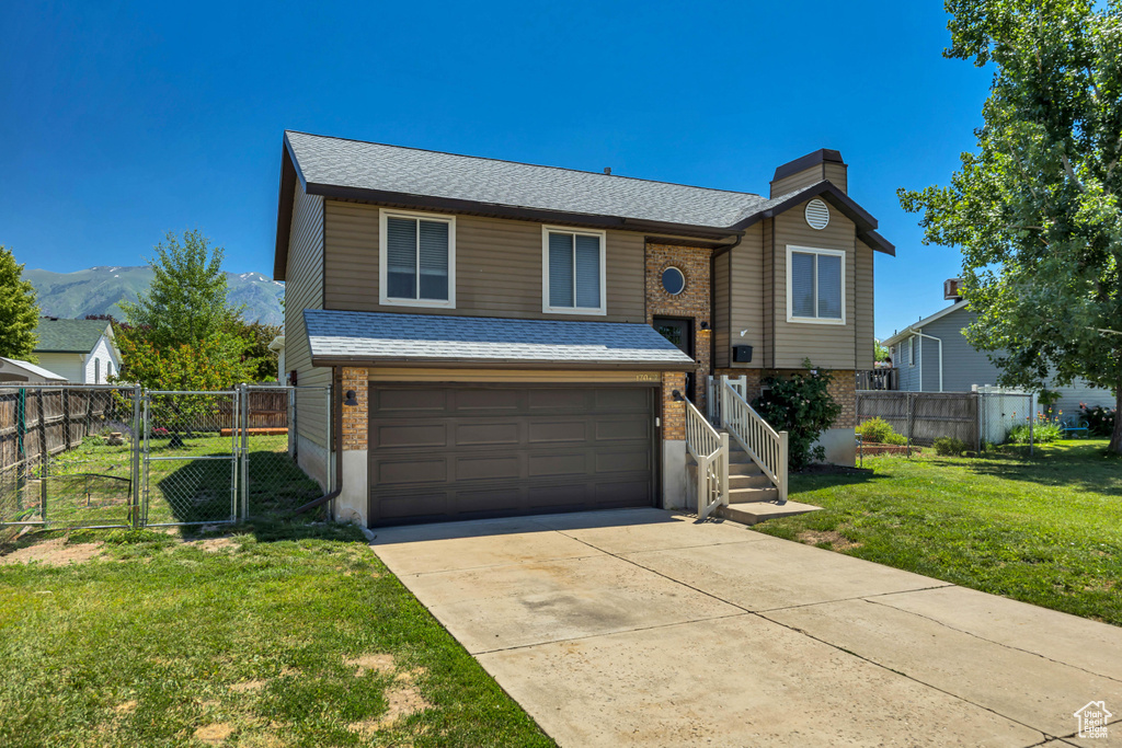 View of front of property featuring an attached garage, a gate, brick siding, concrete driveway, and a chimney