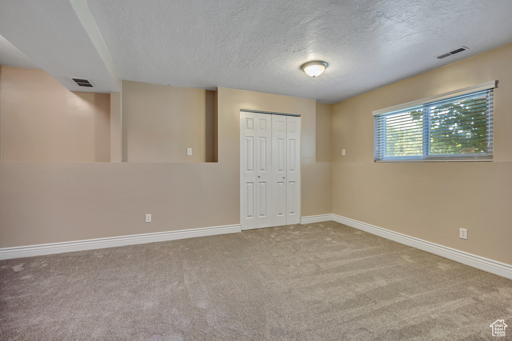 Unfurnished bedroom featuring baseboards, a closet, carpet floors, and a textured ceiling