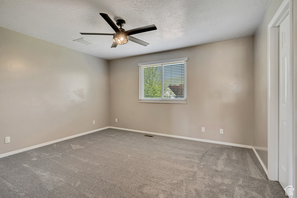 Unfurnished room with ceiling fan, a textured ceiling, carpet flooring, and baseboards