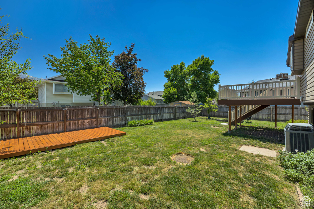 View of yard featuring central AC unit, a wooden deck, and stairs