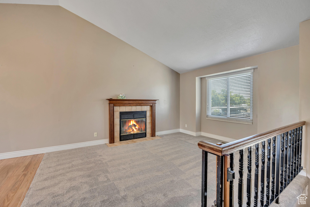 Living area featuring vaulted ceiling, a fireplace, baseboards, and wood finished floors