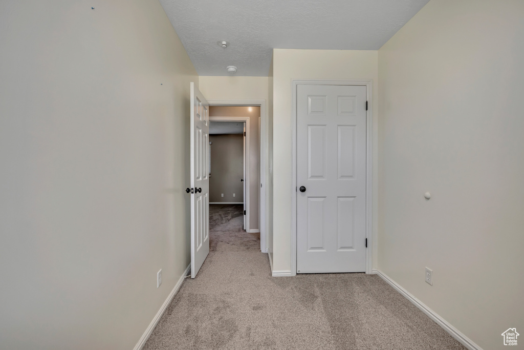 Hallway featuring light carpet and baseboards