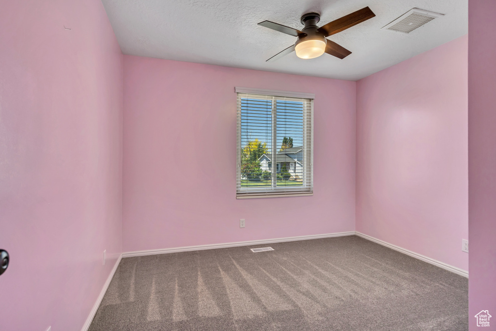 Empty room with a ceiling fan, carpet, baseboards, and a textured ceiling