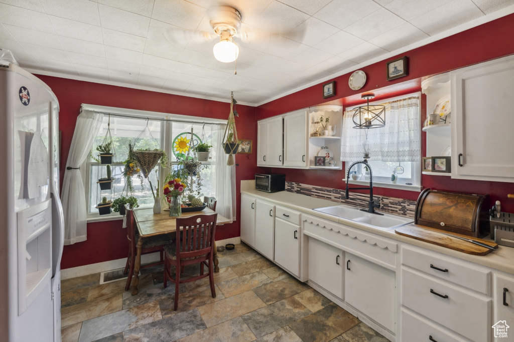 Kitchen featuring open shelves, a sink, white refrigerator with ice dispenser, ceiling fan, and white cabinetry