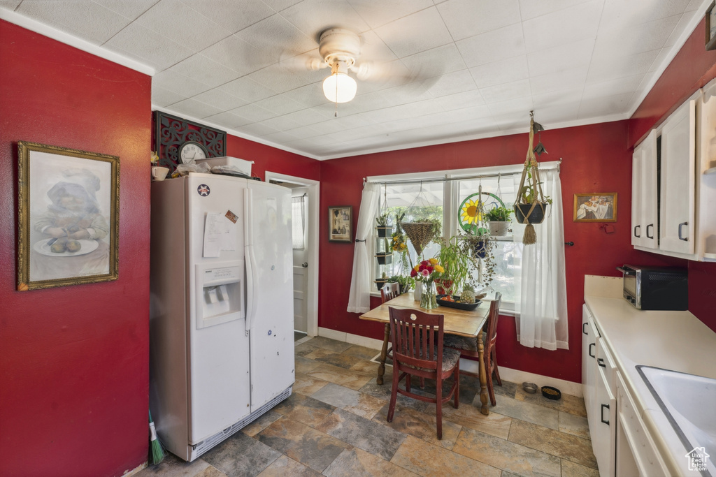 Kitchen with white refrigerator with ice dispenser, stone finish flooring, a sink, light countertops, and ceiling fan