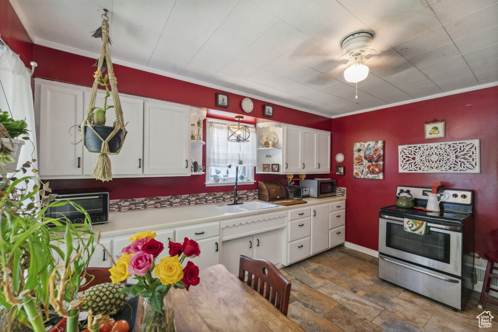 Kitchen featuring appliances with stainless steel finishes, a sink, white cabinets, stone finish floors, and a ceiling fan