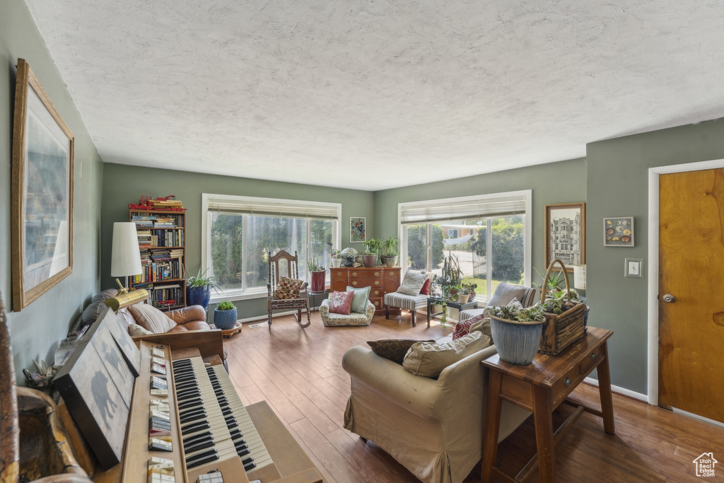 Living area with a textured ceiling, wood-type flooring, and plenty of natural light