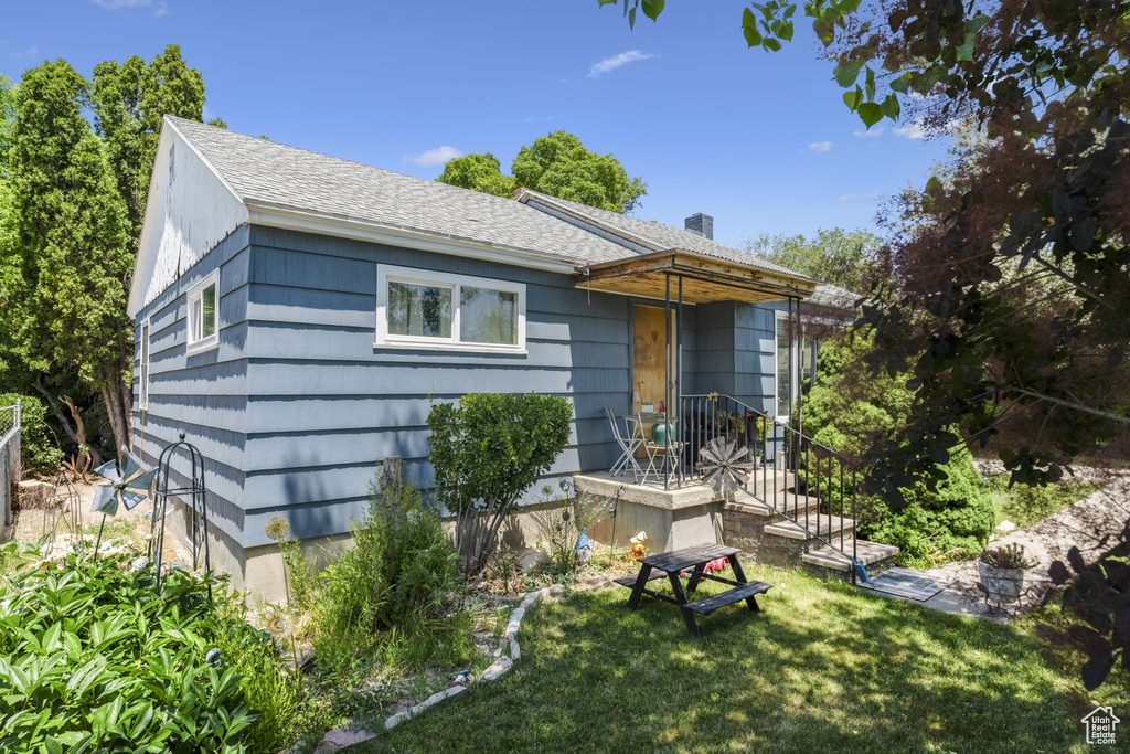 Back of house featuring a lawn and a shingled roof