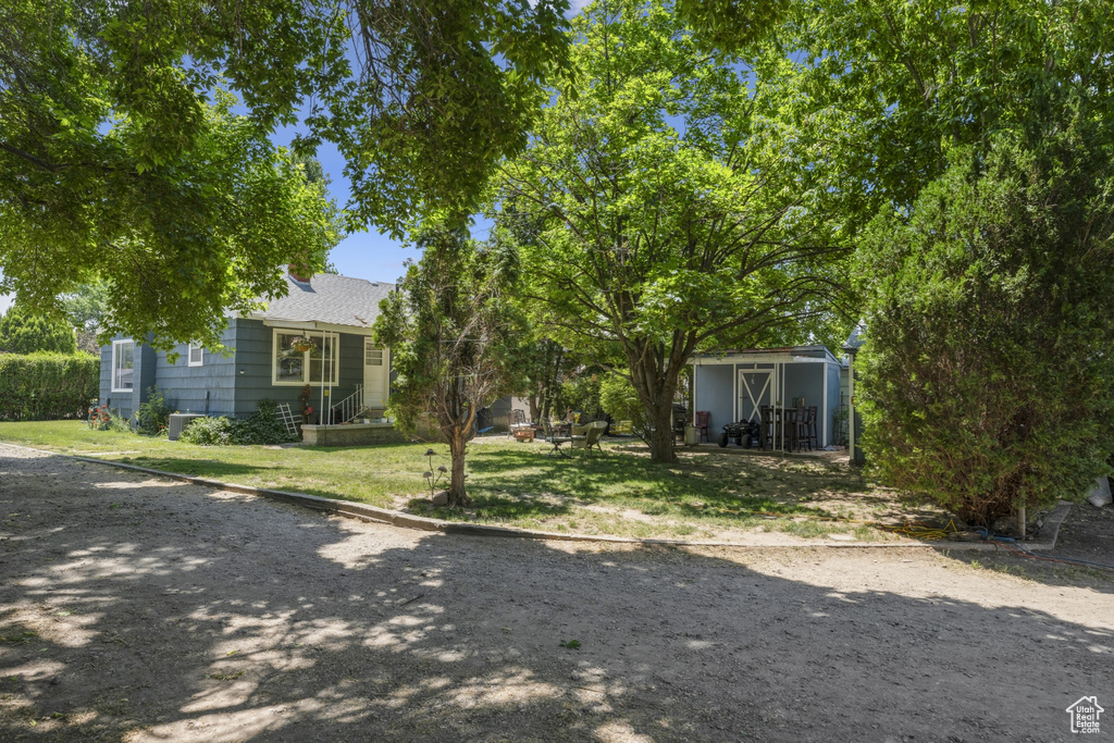 View of front of property featuring an outbuilding, a front lawn, and roof with shingles
