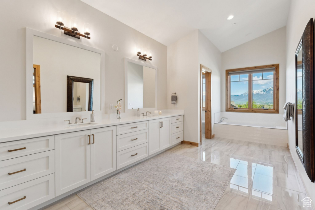 Full bathroom with double vanity, lofted ceiling, and a bath