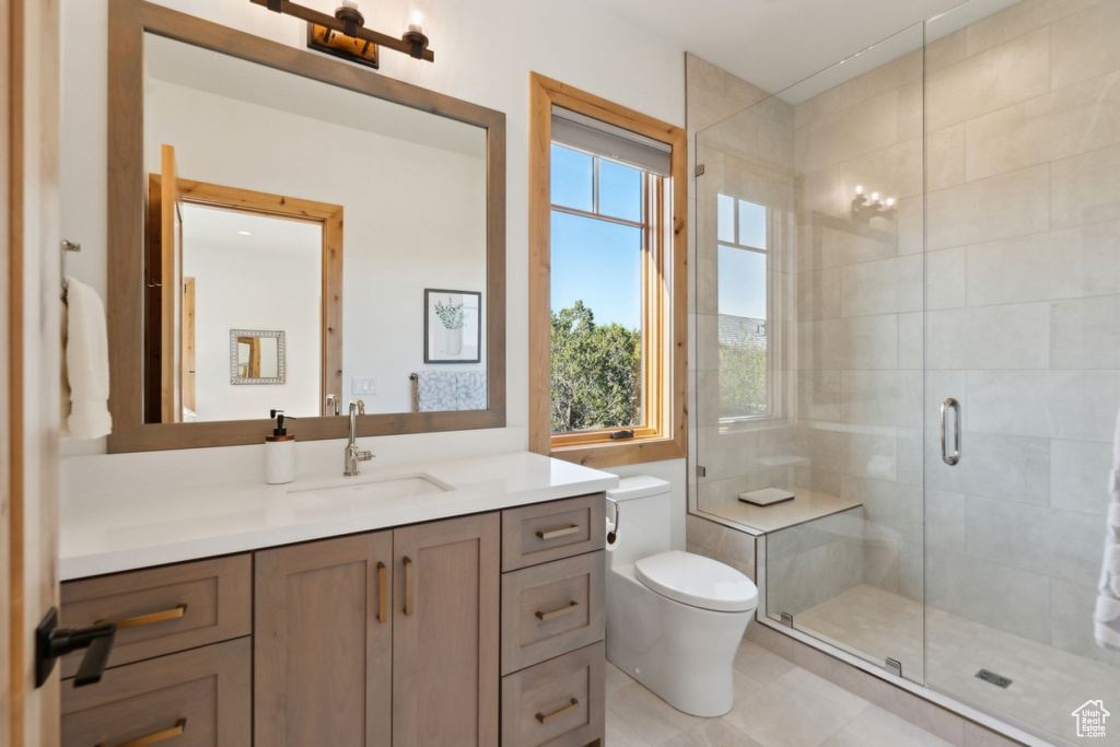 Full bathroom featuring toilet, vanity, a stall shower, and tile patterned floors