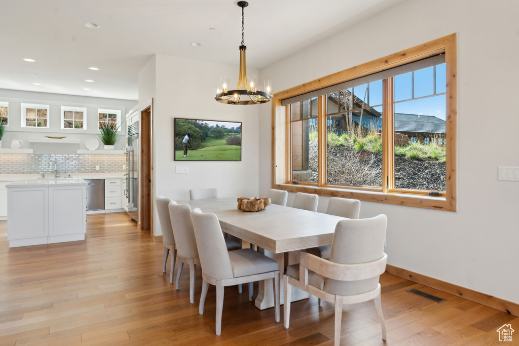 Dining area with a chandelier, light wood-style floors, recessed lighting, and baseboards