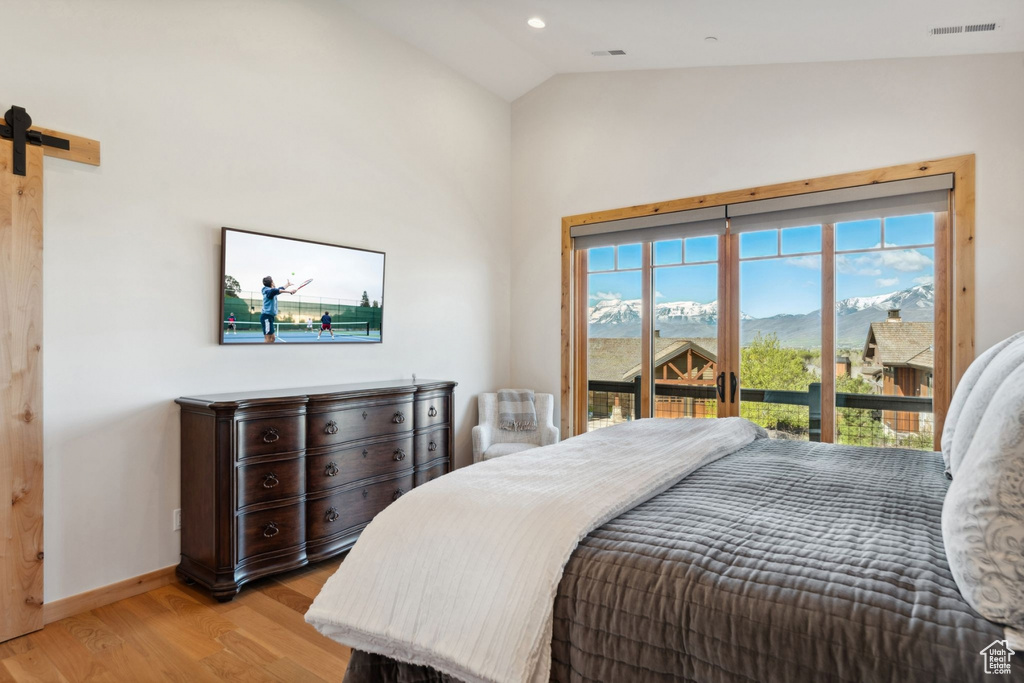 Bedroom featuring light wood finished floors, access to outside, vaulted ceiling, baseboards, and a mountain view