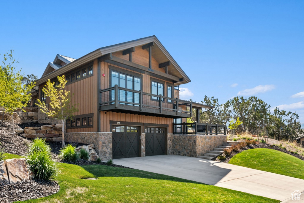 View of front of home with a front lawn, stone siding, concrete driveway, stairs, and a garage