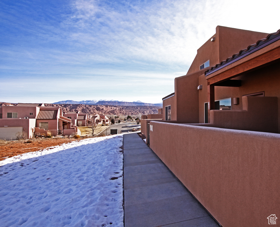 Snow covered property featuring a residential view, a mountain view, and stucco siding