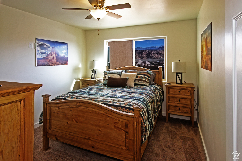 Bedroom with dark carpet, baseboards, and ceiling fan