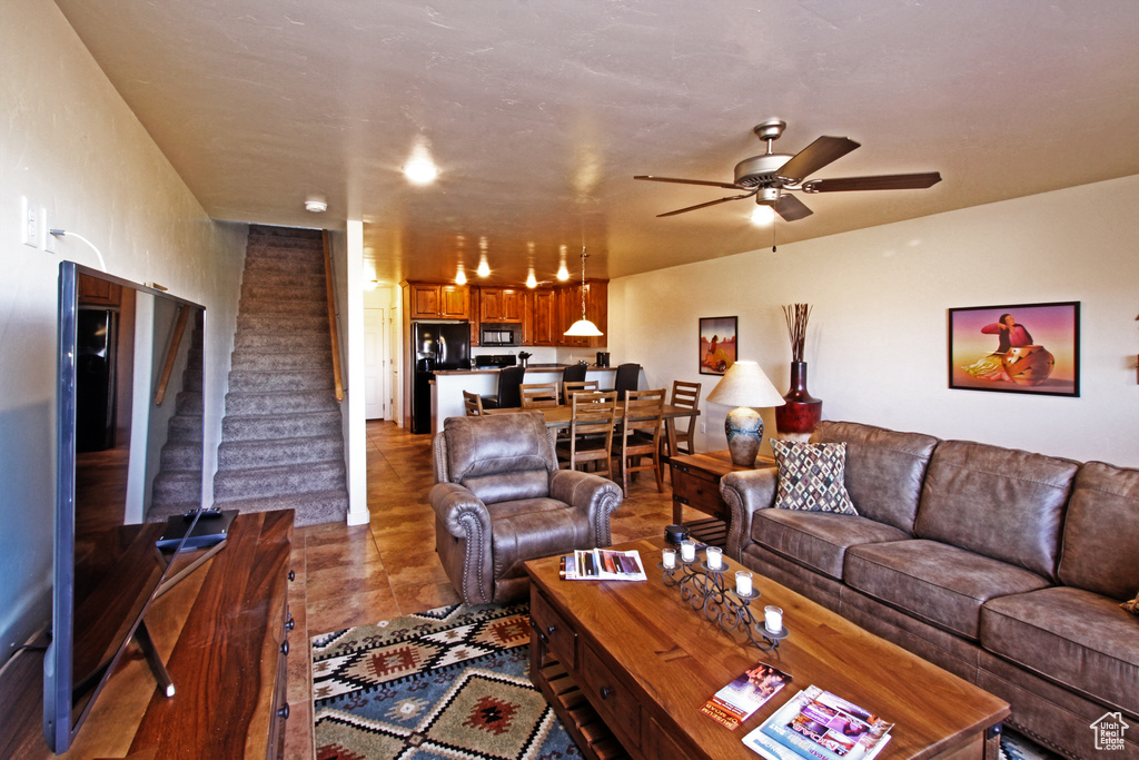Living area featuring a ceiling fan and stairs