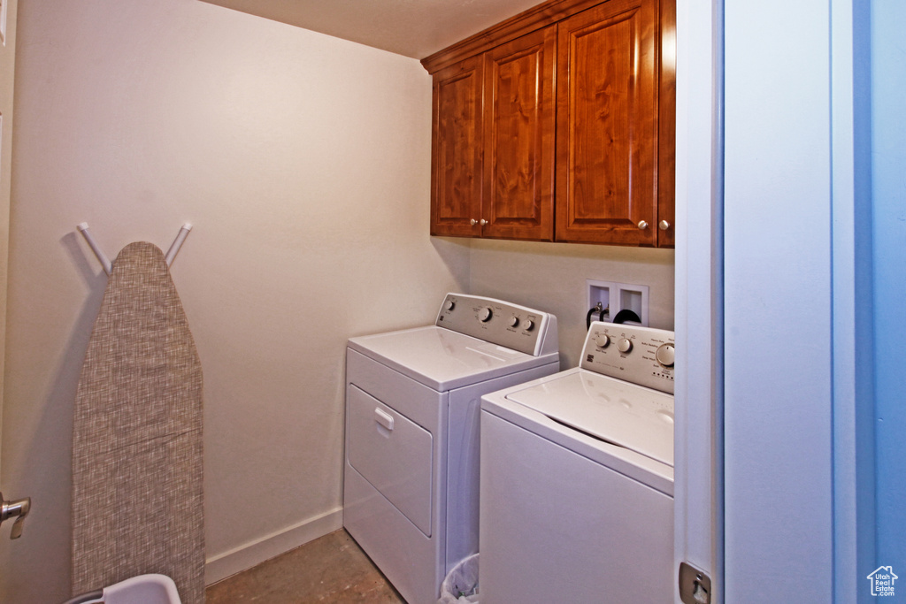 Washroom featuring cabinet space, separate washer and dryer, and baseboards