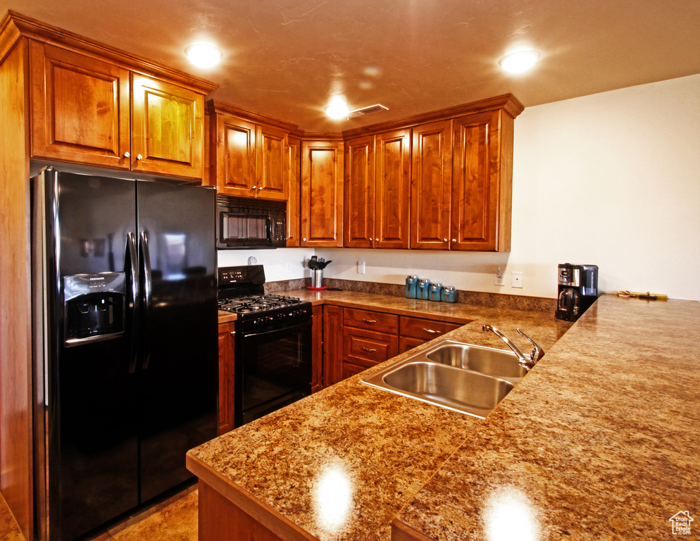 Kitchen with black appliances, a sink, brown cabinetry, a peninsula, and recessed lighting