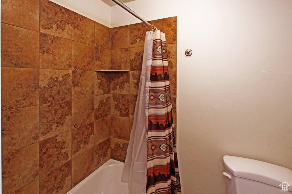 Full bath with shower / bath combo with shower curtain and toilet
