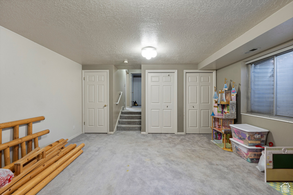 Recreation room with carpet and a textured ceiling