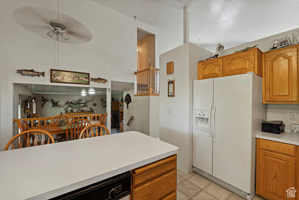 Kitchen featuring white refrigerator with ice dispenser, dishwasher, light countertops, ceiling fan, and brown cabinets