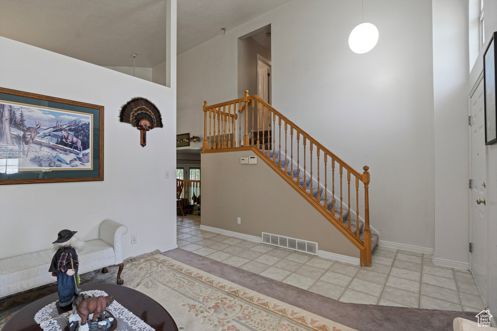 Entrance foyer with tile patterned floors, stairway, a high ceiling, and baseboards