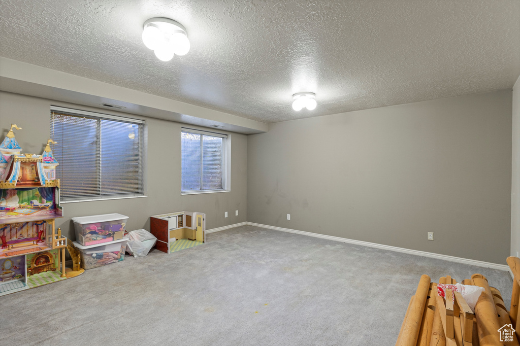 Recreation room featuring carpet floors, a textured ceiling, and baseboards